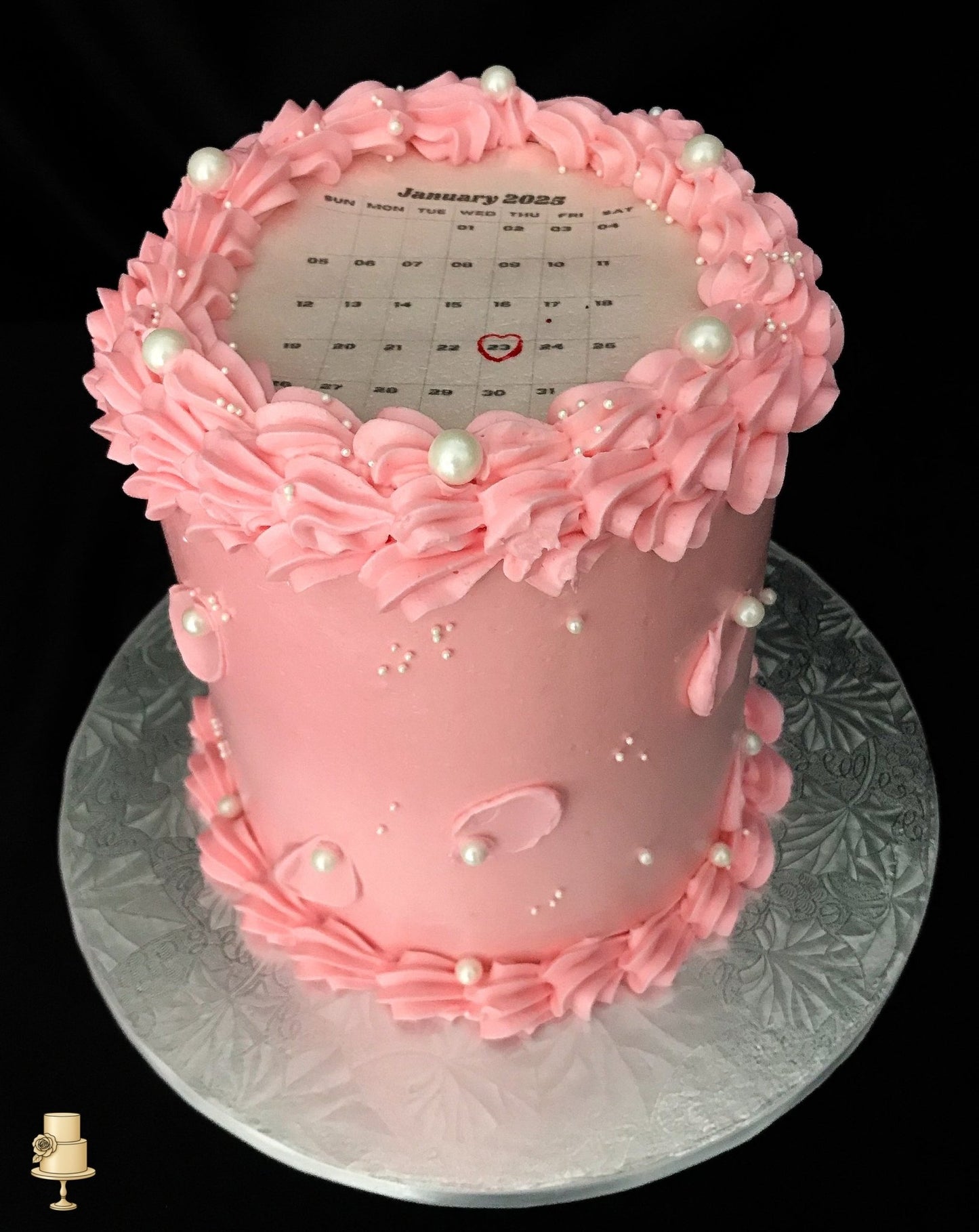 Pink cake with ruffled frosting and a calendar on top