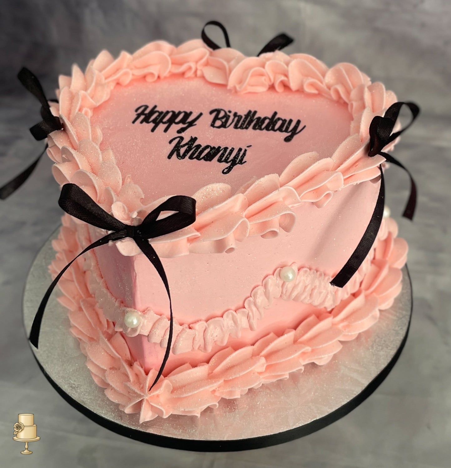 Heart shape vintage cake with pink buttercream icing and black fabric bows