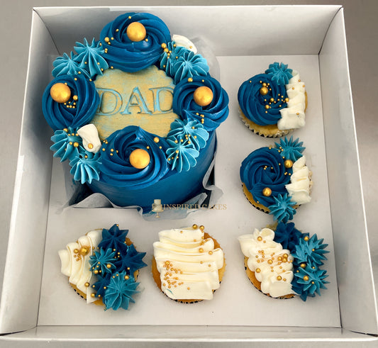 Decorative cake and cupcakes with blue and white frosting in a box, featuring the word 'DAD'.