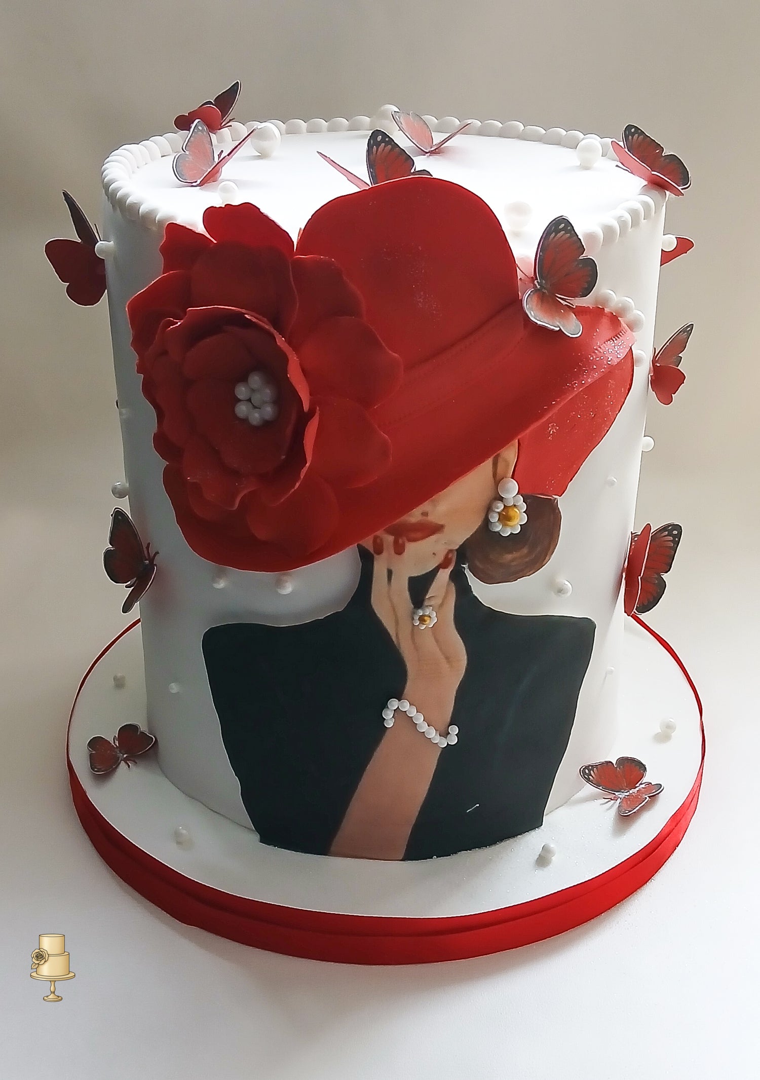 Decorative cake with a woman wearing a red hat, surrounded by butterflies and flowers.