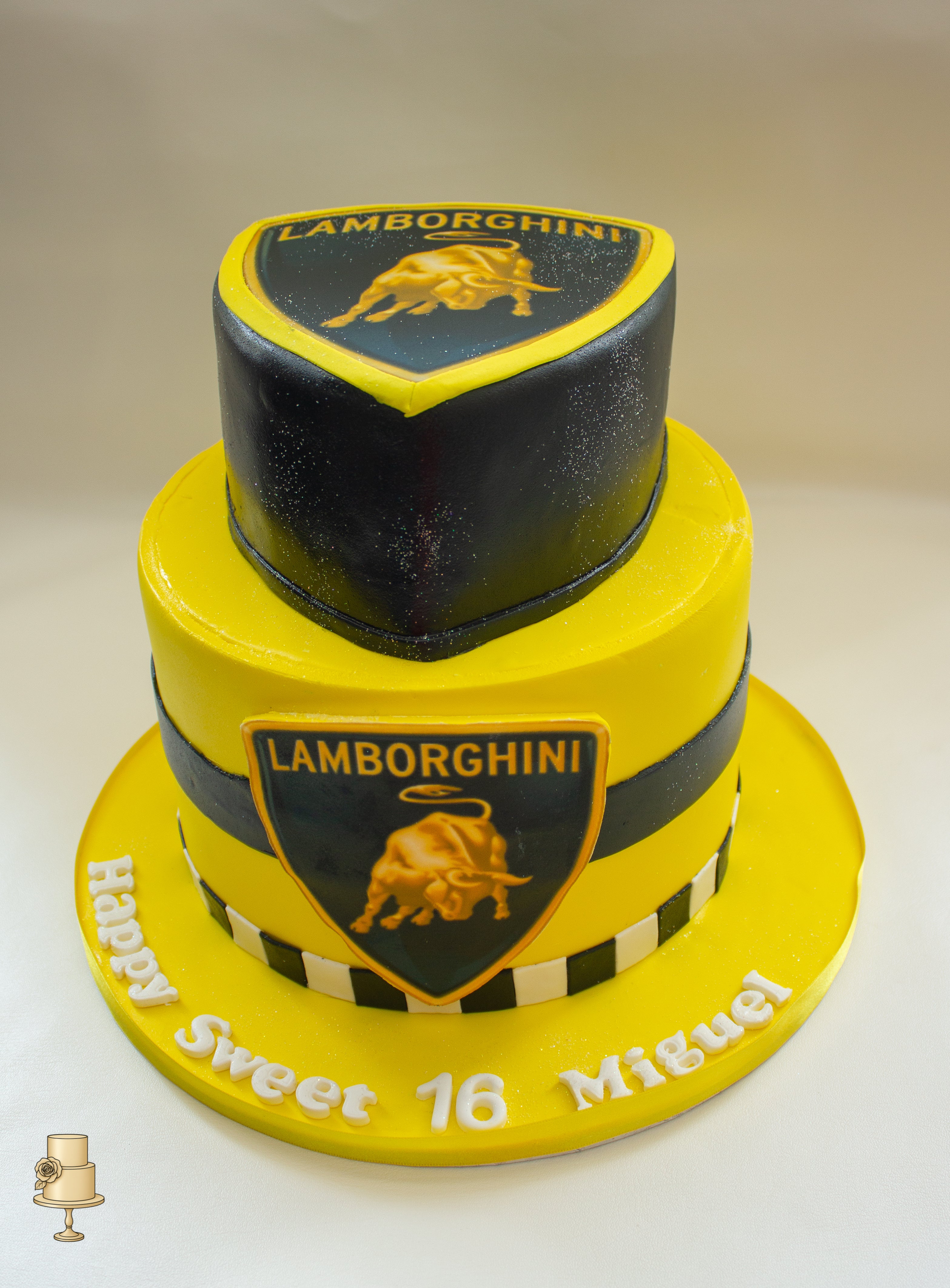 Two-tiered cake with Lamborghini logo and 'Happy Sweet 16 Miguel' text on a white background